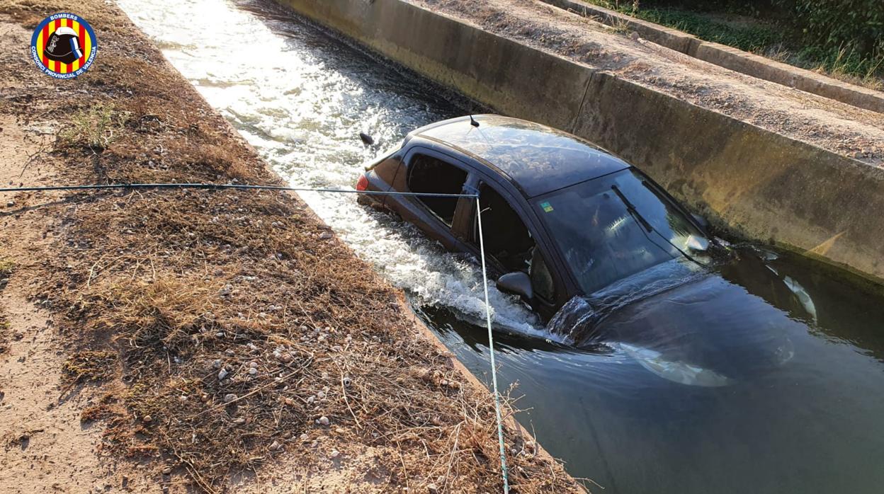 El coche sumergido en el agua y sujetado con cuerdas, durante el rescate