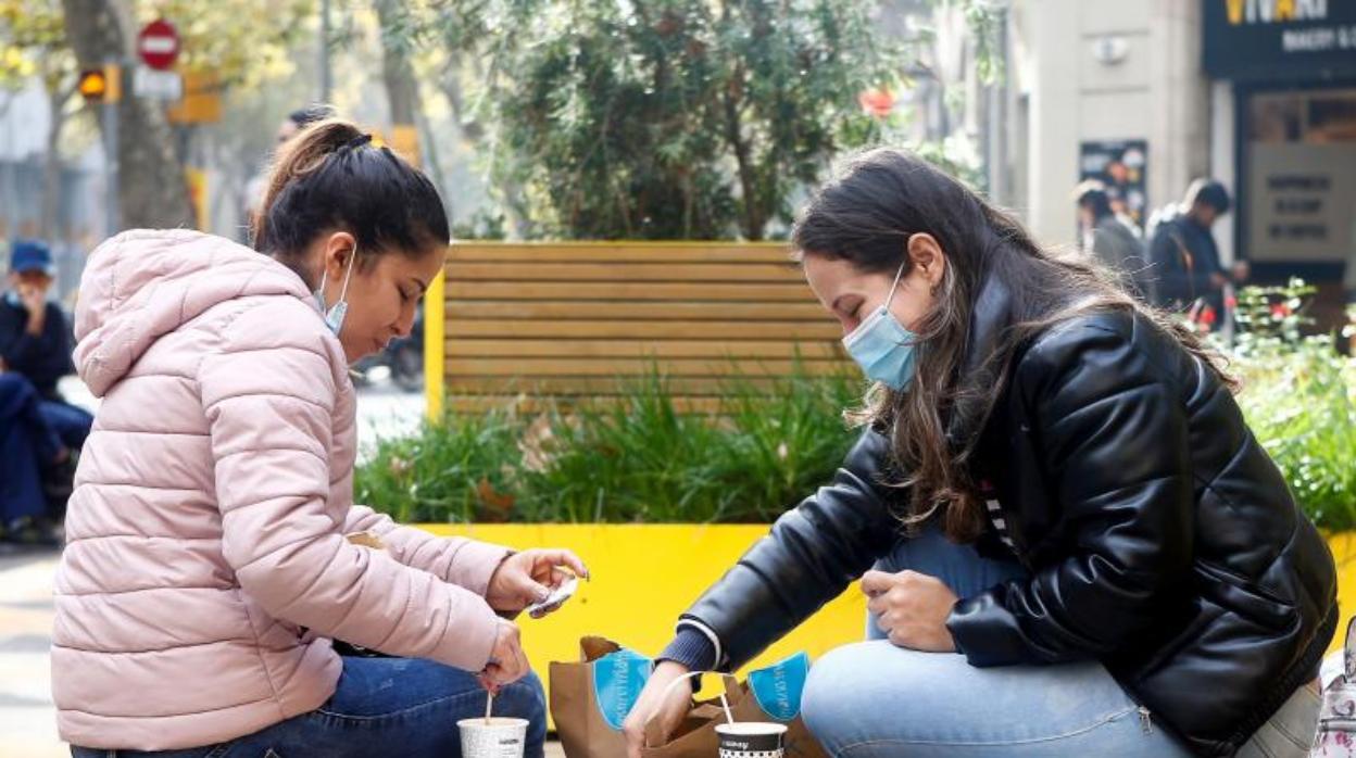 Dos mujeres, desayunando esta mañana en un banco de Barcelona