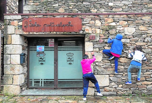 Varios niños juegan a trepar la fachada de la sala polivalente del Ayuntamiento