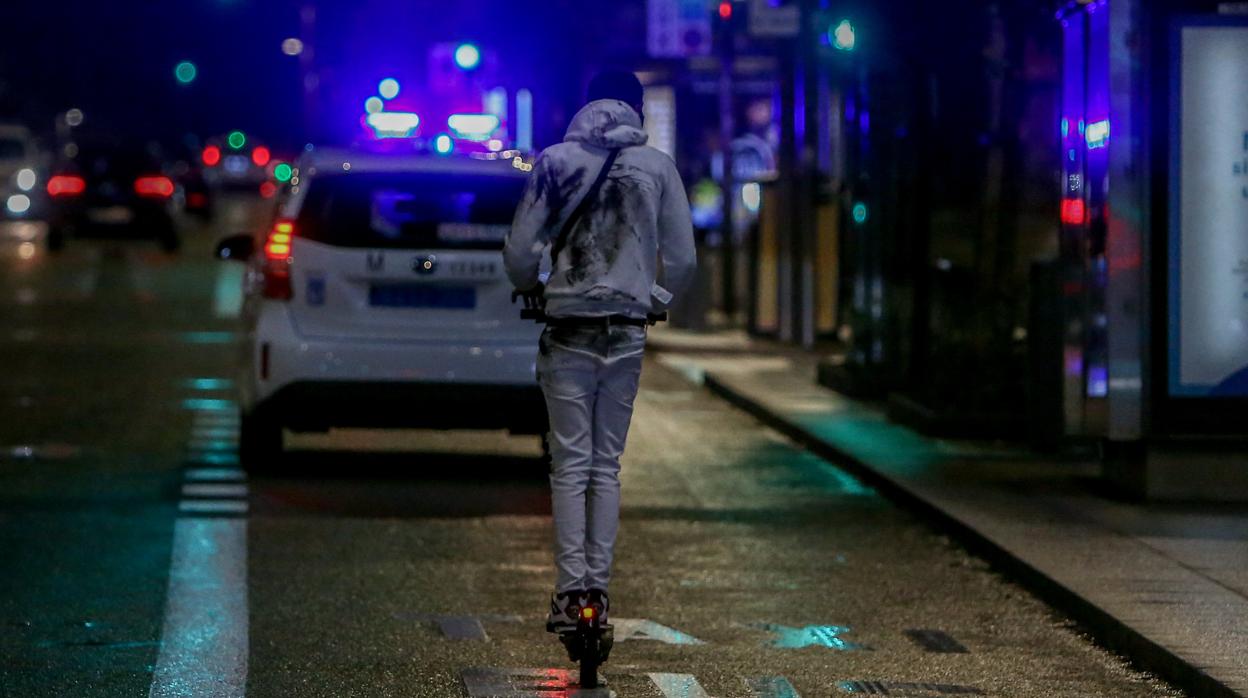 Un joven en patinete eléctrico circula por el centro de la capital durante la primera noche de toque de queda