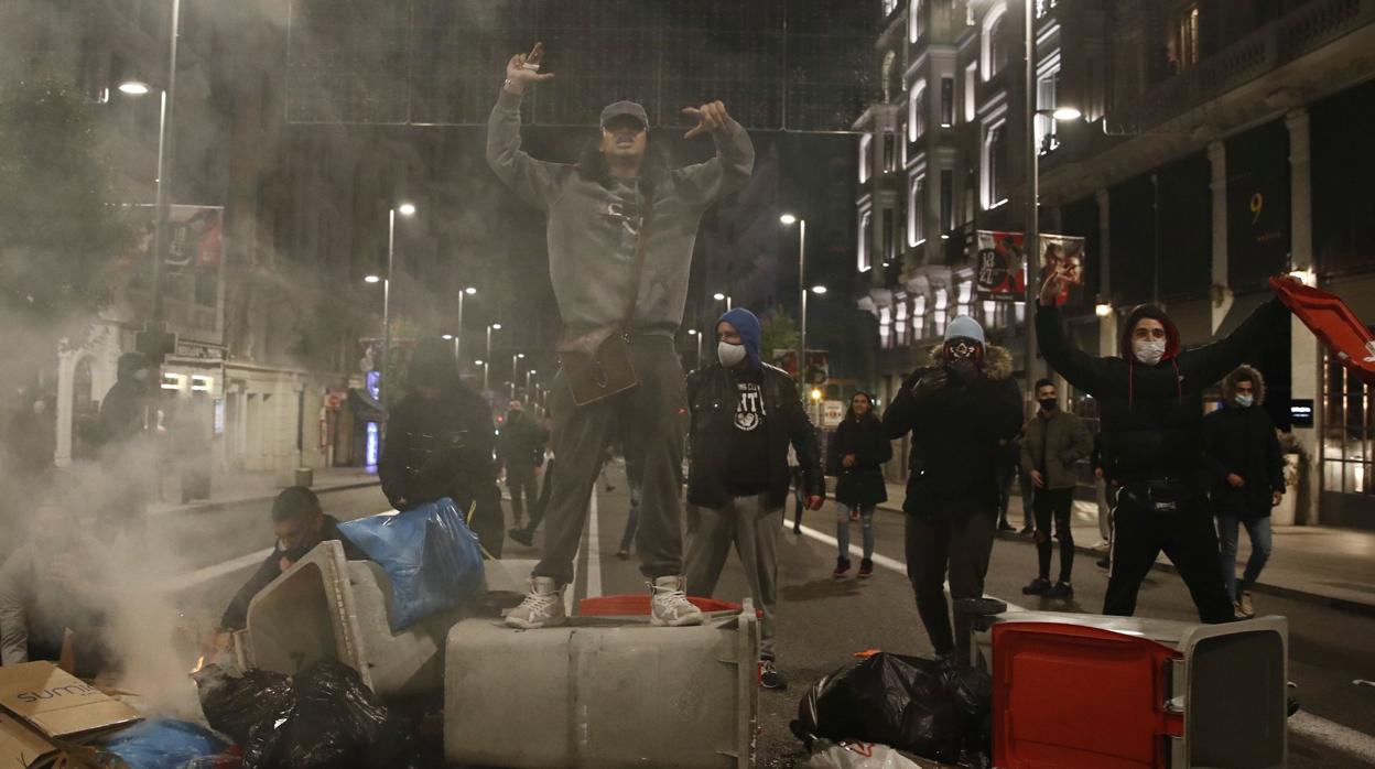 Varios jóvenes organizan una barricada durante los disturbios de la noche del sábado en Madrid