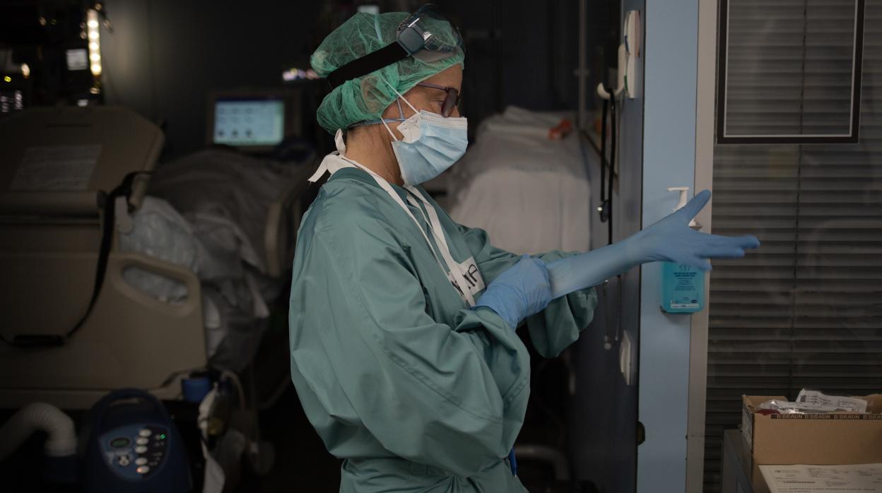 Una sanitaria se pone unos guantes en la Unidad de Cuidados Intensivos del Hospital de Sant Pau