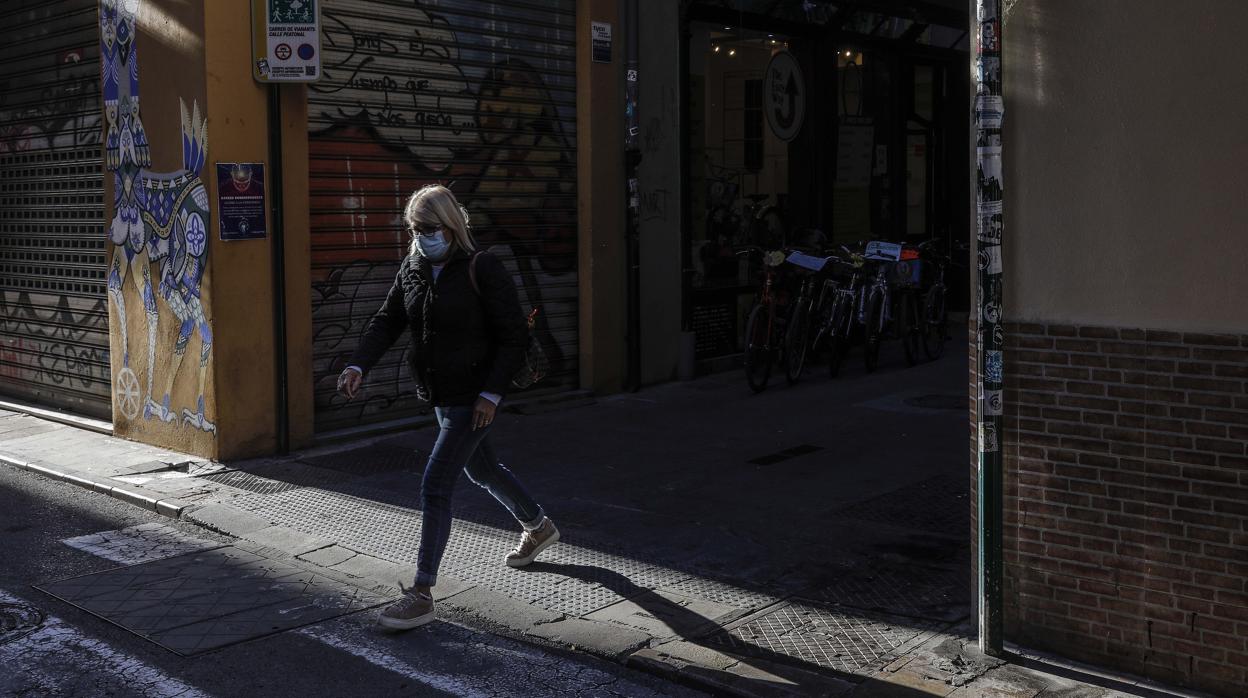 Imagen de una mujer paseando por Valencia con mascarilla por el coronavirus