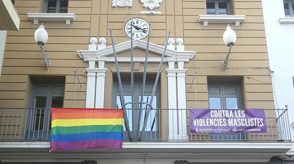 Imagen difundida por la CUP de Pedreguer en sus redes sociales de la fachada del Ayuntamiento con la bandera LGTBI y una pancarta contra la violencia machista