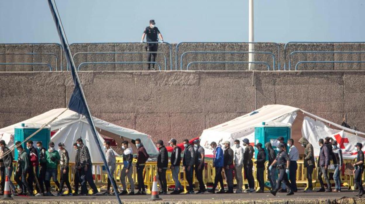 Un agente de la Policía Nacional observa a los inmigrantes instalados en el campamento del muelle de Arguineguín (Gran Canaria)