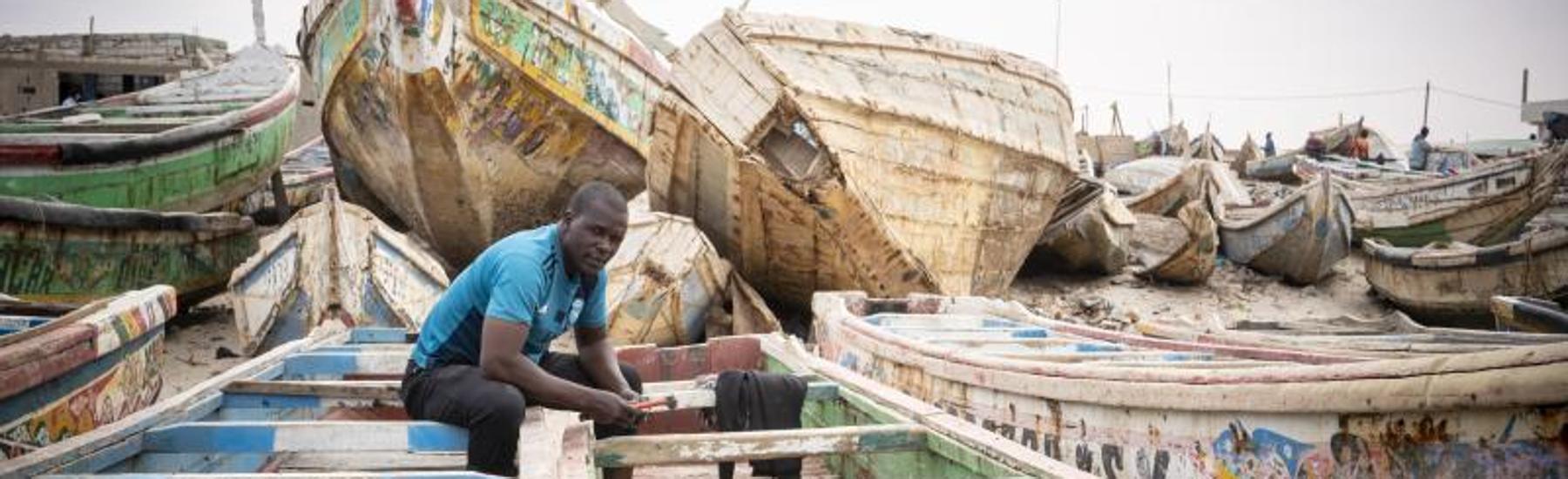 Los cayucos más deteriorados se reparan varados en la playa de Nuakchot