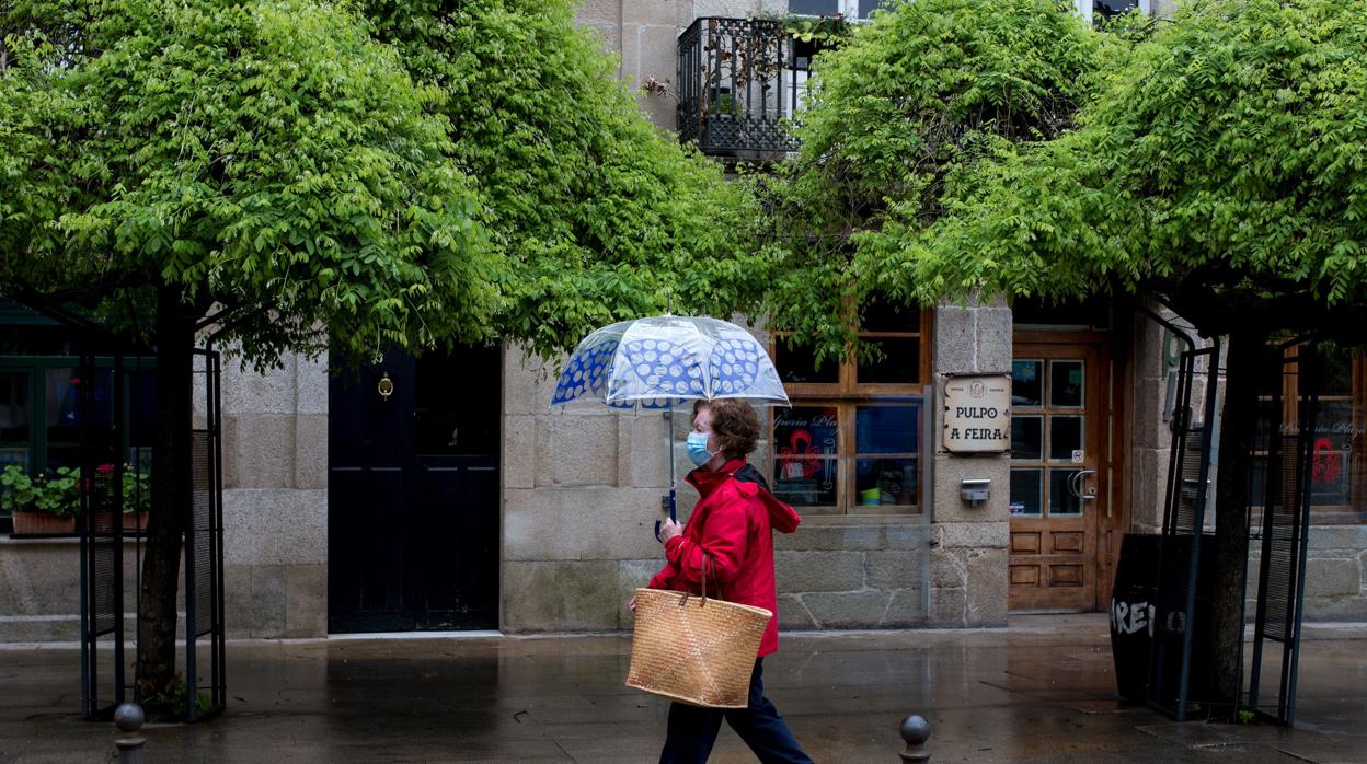 Una mujer se resguarda de la lluvia bajo su paraguas