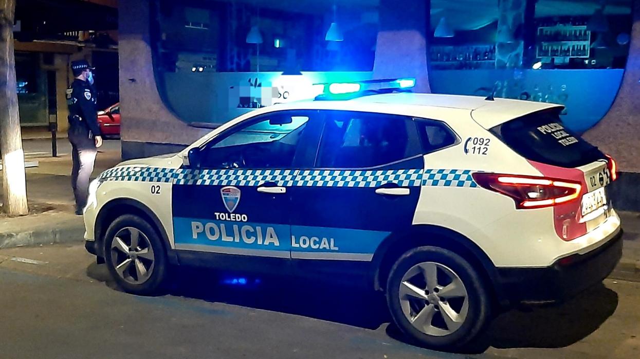 Un coche de la Policía local y un agente, delante del bar que los dos detenidos intentaron asaltar presuntamente