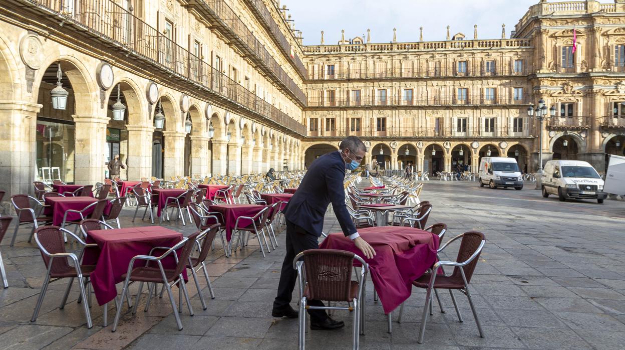 Un trabajador de la hostelería coloca las mesas en la Plaza Mayor de Salamanca