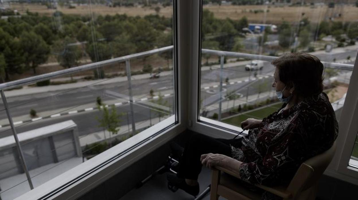 Una mujer mayor sola mira por la ventana