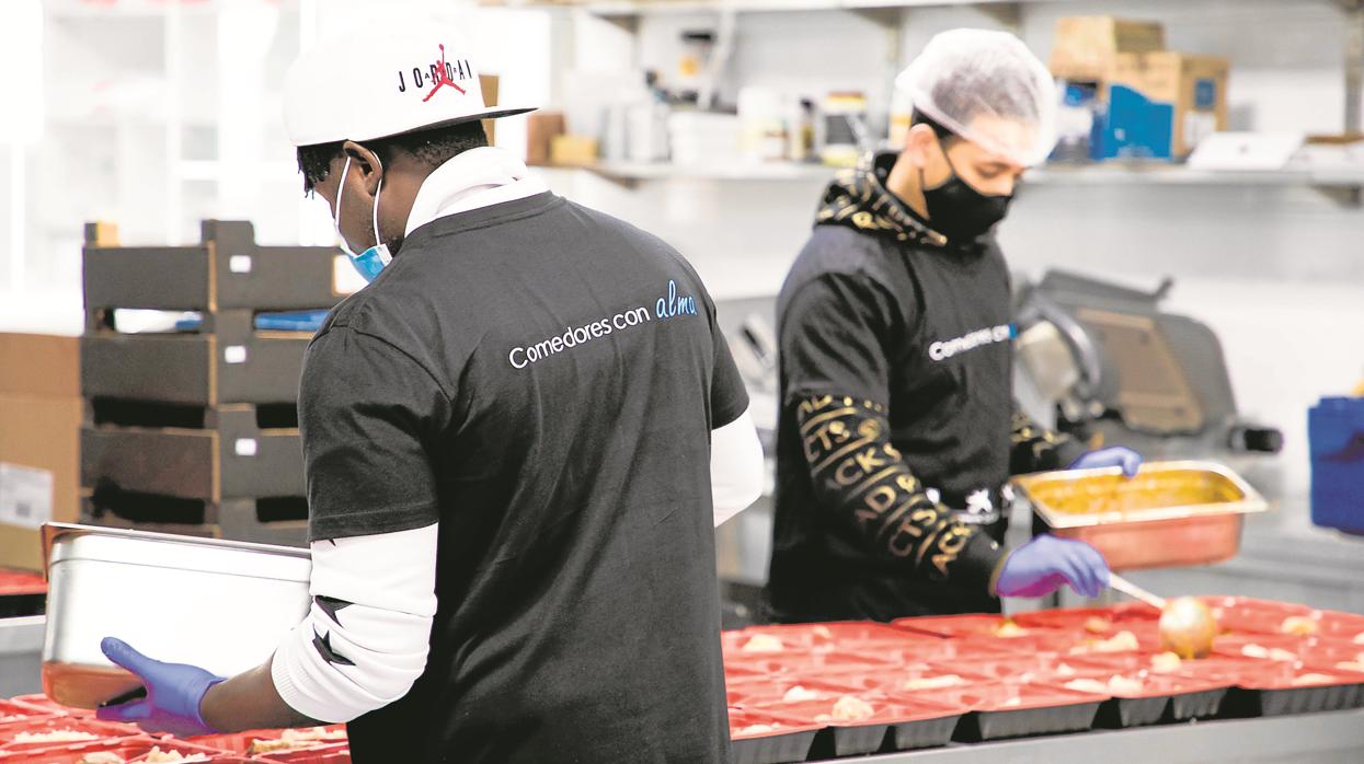 Dos voluntarios preparan los menús de Nochebuena