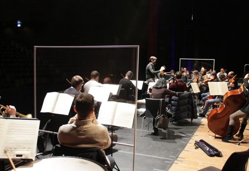 Ensayo en el auditorioi. Los músicos con instrumentos de viento tras grandes mamparas