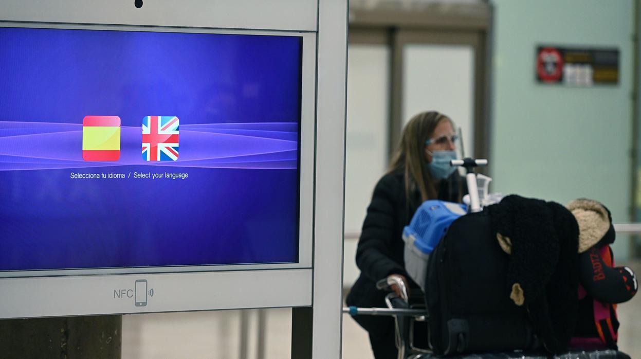 Una mujer porta varias maletas en el Aeropuerto de Barajas