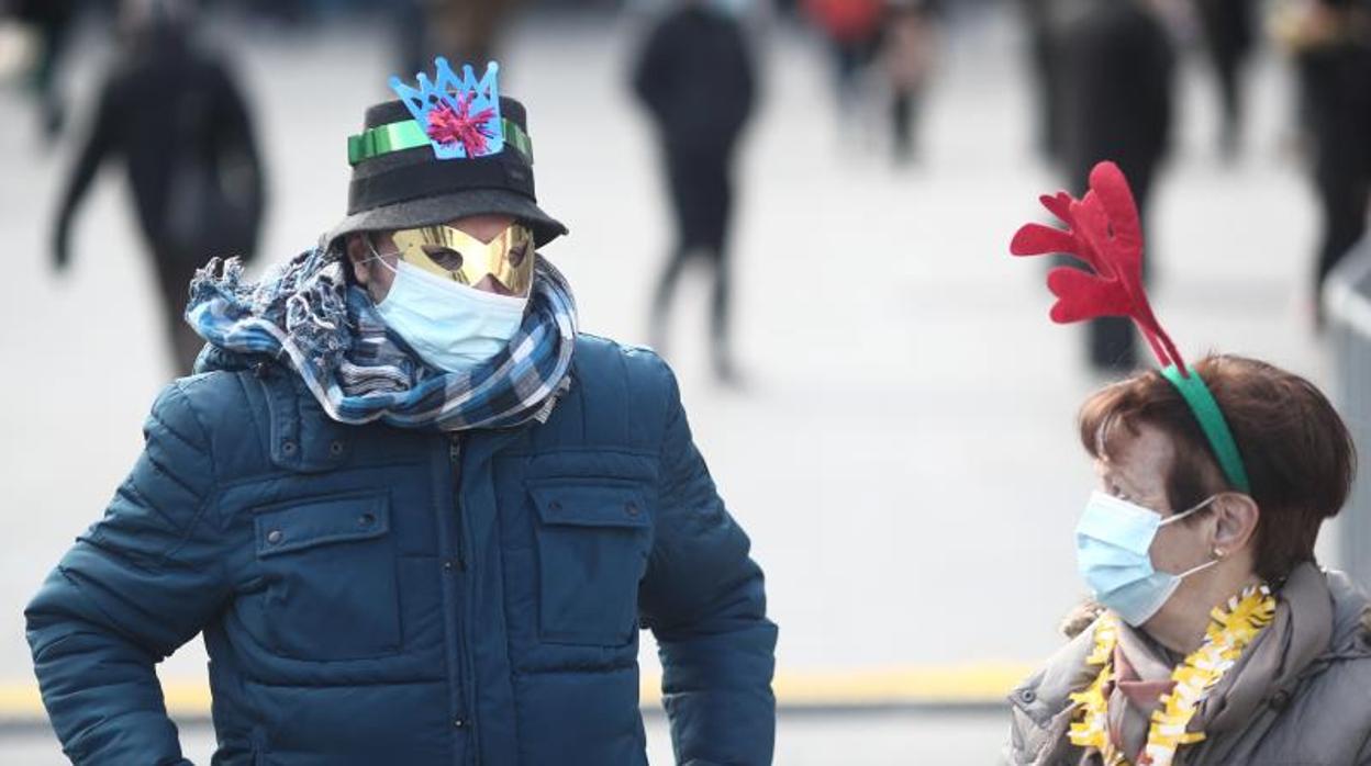 Dos paseantes por la Puerta del Sol, ataviados con adornos navideños