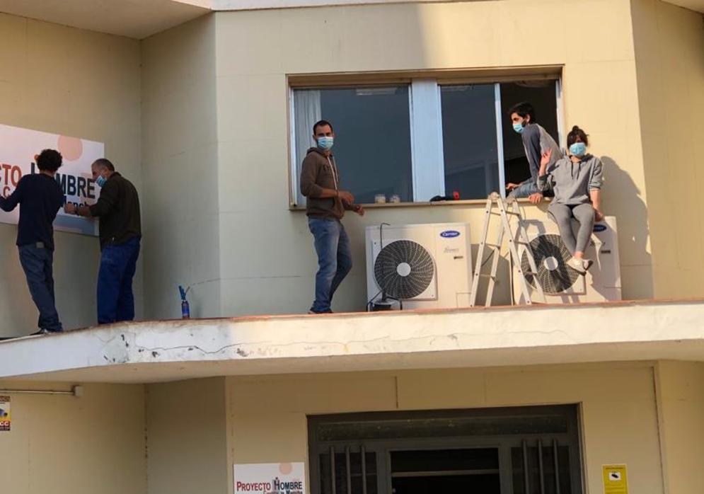 Trabajadores del centro instalan en la fachada del edificio el cartel de la organización