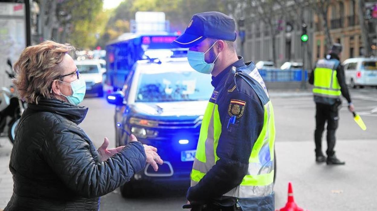 Una vecina pregunta a un agente de la Policía Municipal en una zona básica de salud con restricciones en Madrid