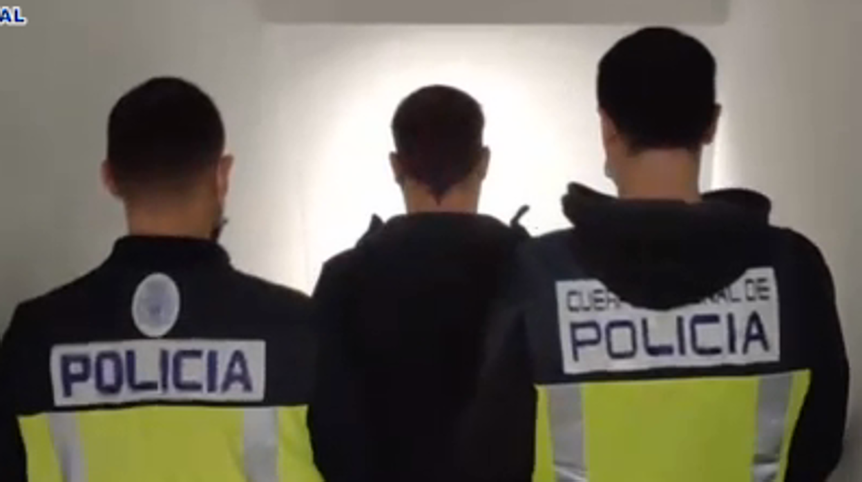 El arrestado es conducido por dos agentes en dependencias policiales