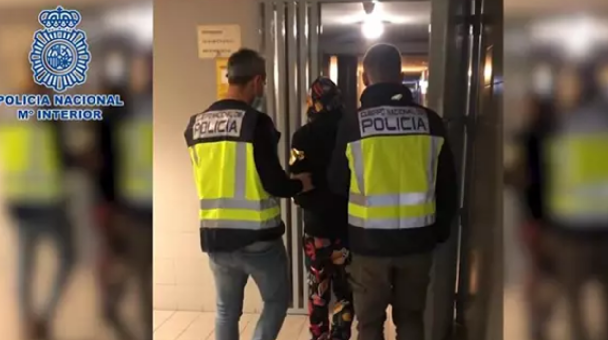 Dos agentes conducen a uno de los detenidos a las dependencias policiales