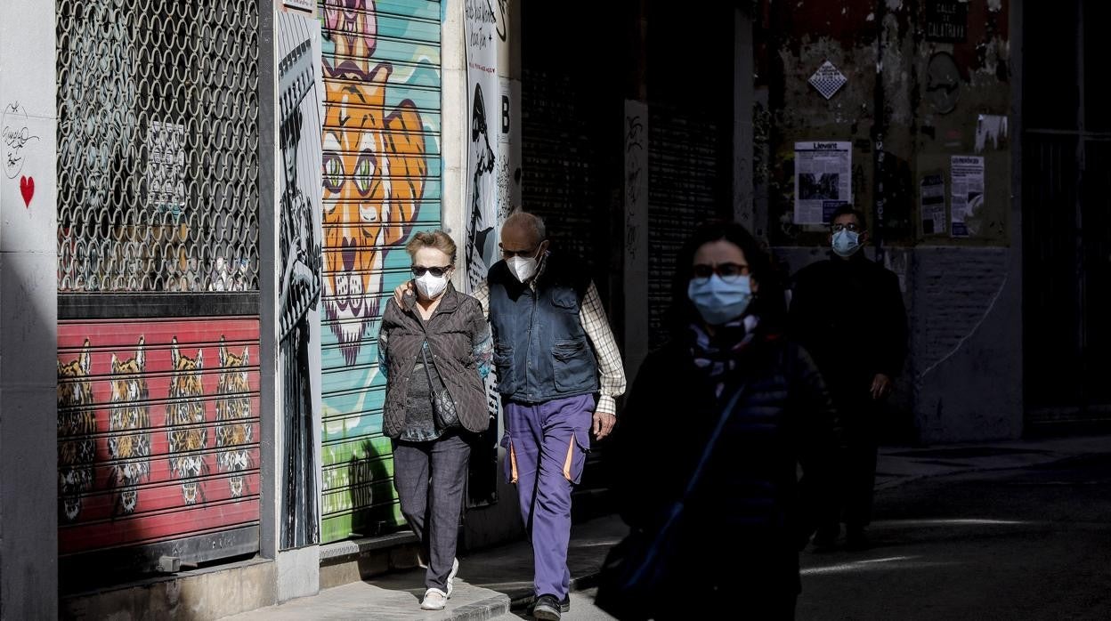 Imagen de personas con mascarilla paseando por las calles de Valencia