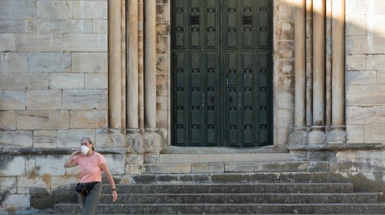 Una peregrina pasa frente a la fachada de la Iglesia de San Nicolao, en Portomarín