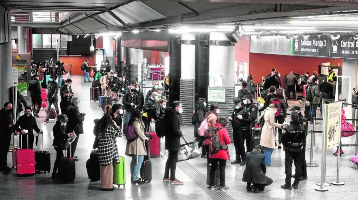 Varias personas esperan en un control de pasajeros en la estación de Renfe de Madrid Puerta de Atocha
