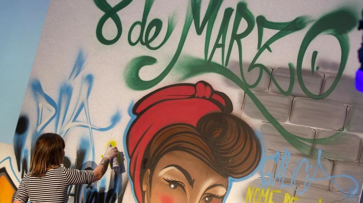 Una mujer pindando un mural para reivindicar el Día de la Mujer