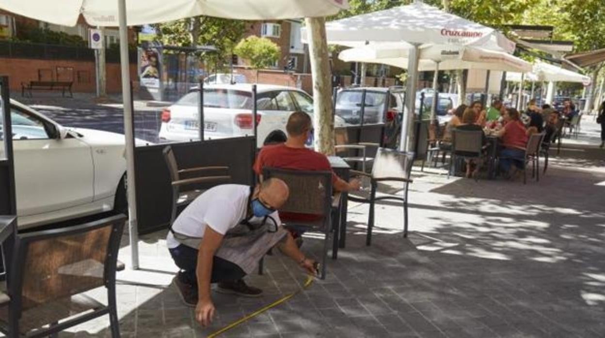 Un camarero mide la distancia entre las mesas en un terraza de Madrid