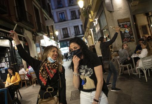 Otras dos ciudadanas galas muestran con su móvil la contenida fiesta madrileña