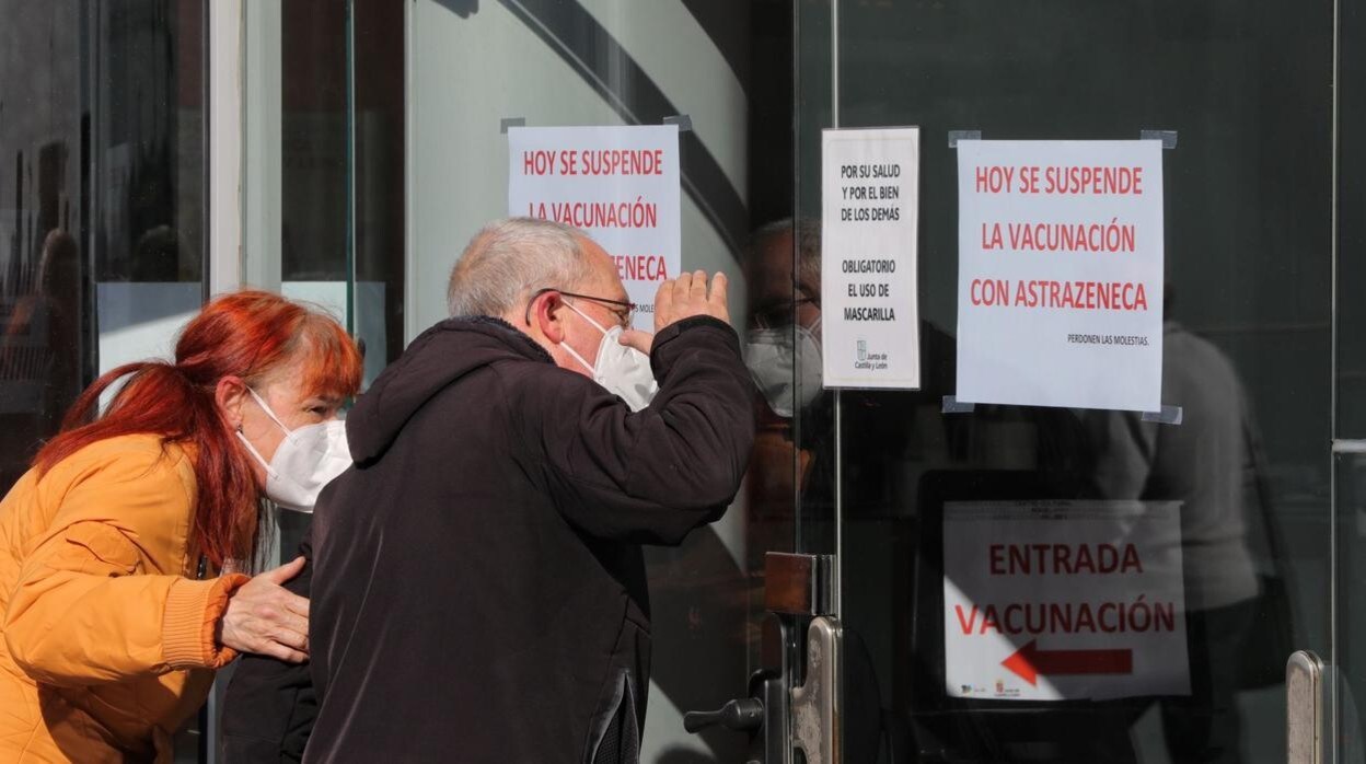 Dos de los afectados leen los carteles puestos esta mañana en las puertas del Auditorio Miguel Delibes, lugar para la vacunación masiva en Valladolid