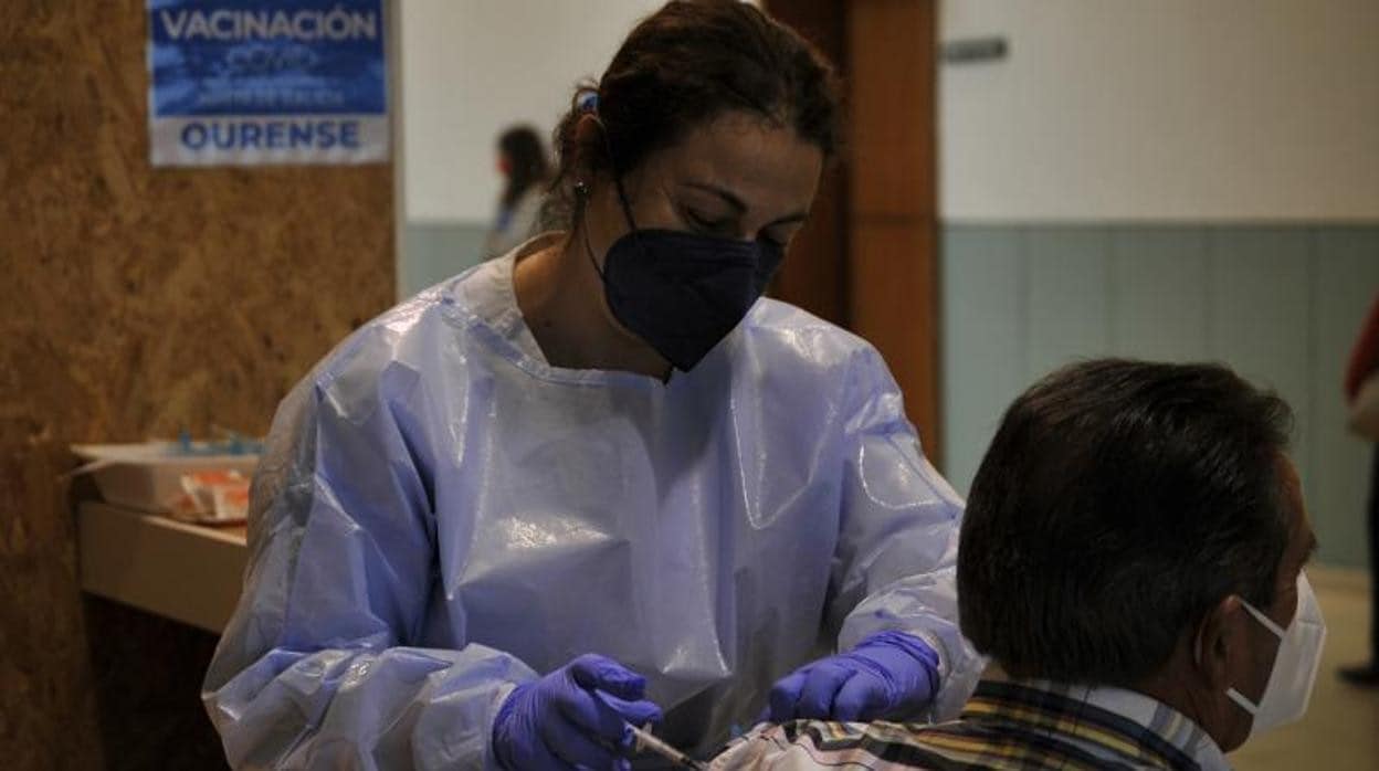 Una sanitaria inyecta a un paciente la primera dosis de la vacuna AstraZeneca en el recinto de Expourense