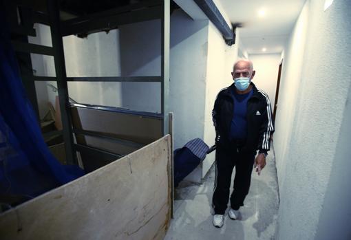 Un vecino sube la escalera de caracol instalada junto al hueco del ascensor, abandonado por las subcontratas tras los impagos de Inver S.L., apenas protegido por unas tablas de pladur