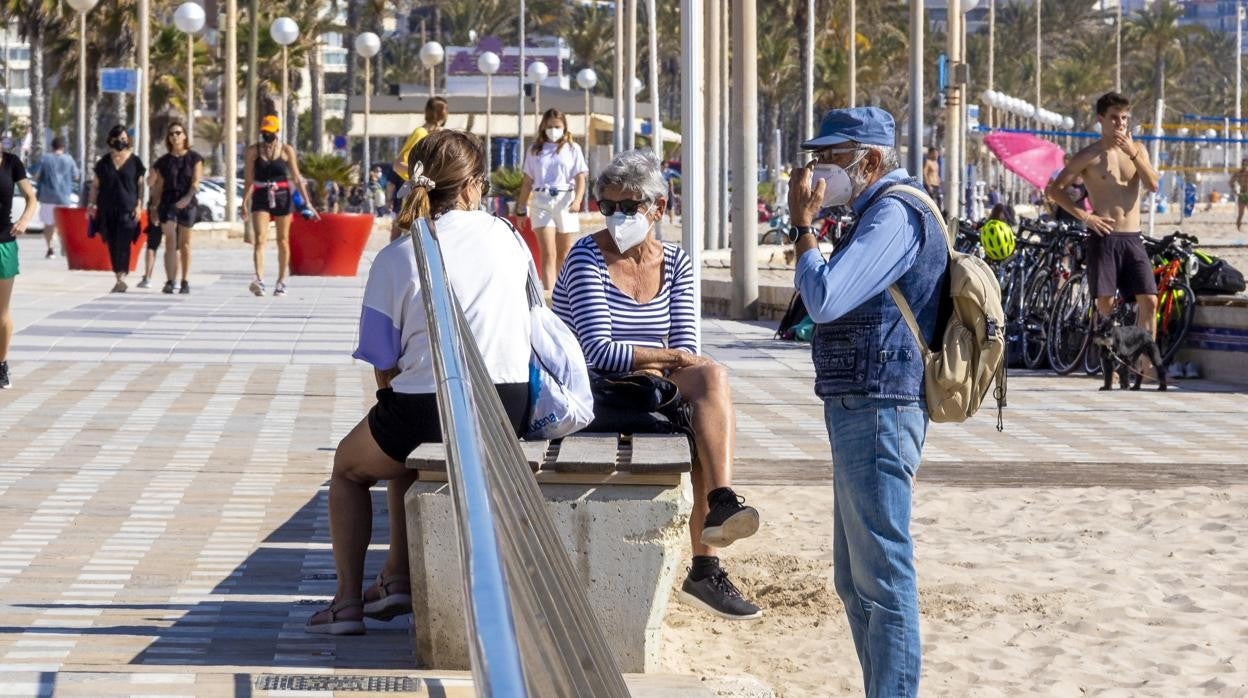 Imagen de personas con mascarilla tomada este sábado en la playa de San Juan de Alicante