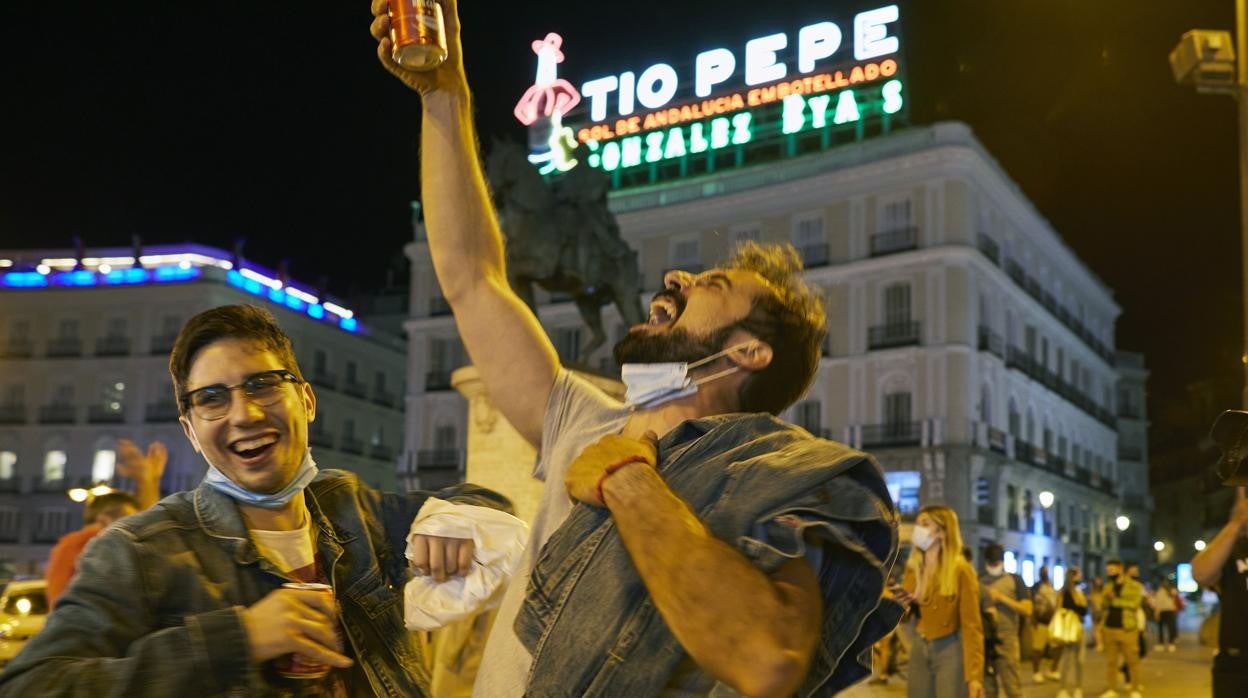 Dos hombres celebra, cerveza en mano, el final del estado de alarma en la Puerta del Sol