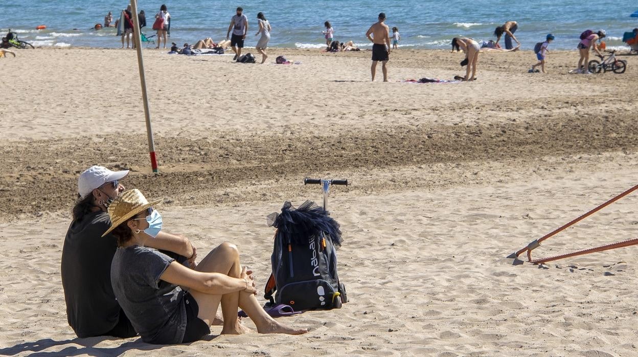 Imagen de dos personas con mascarilla en la playa de San Juan de Alicante