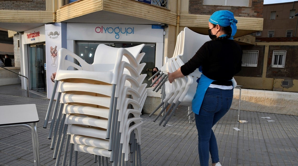 Una empleada recoge las mesas de una terraza