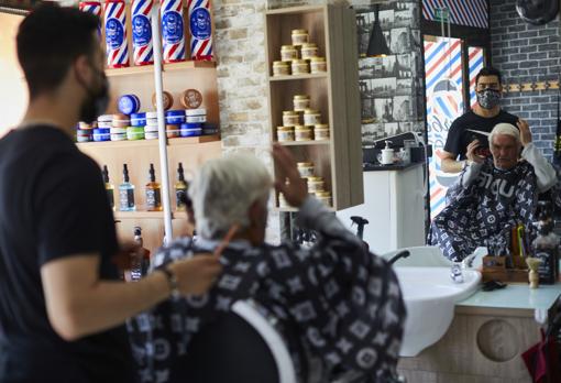 Omar atiende a un cliente en su barbería, en Torrelaguna