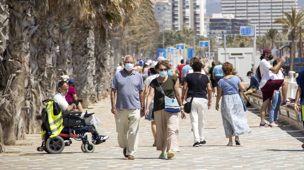 Imagen de personas paseando con mascarilla por la playa de San Juan de Alicante