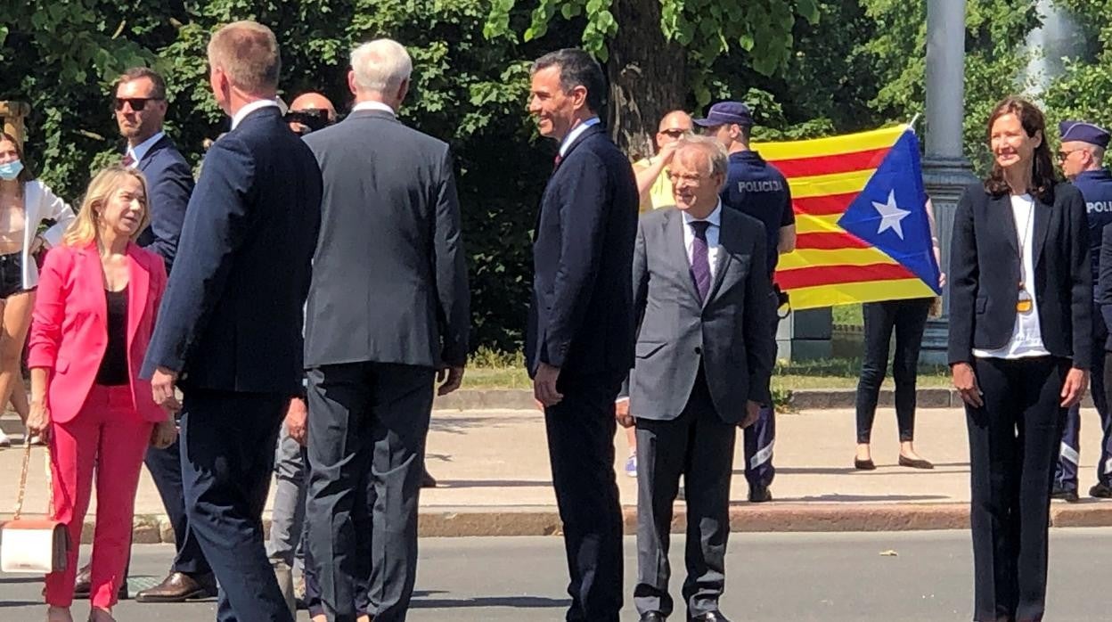 Pedro Sánchez durante la ofrenda floral en Riga, con la bandera independientista catalana de fondo
