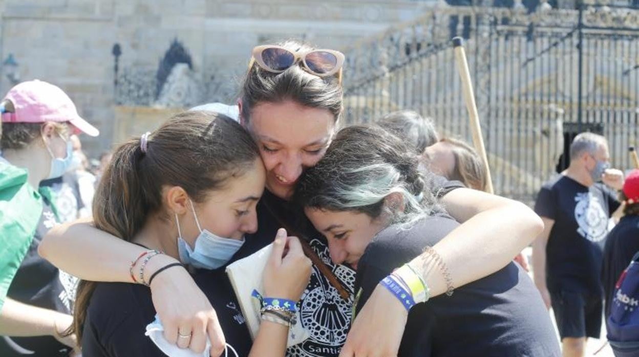 Una mujer abraza a dos jóvenes en la Plaza del Obradoiro de Santiago