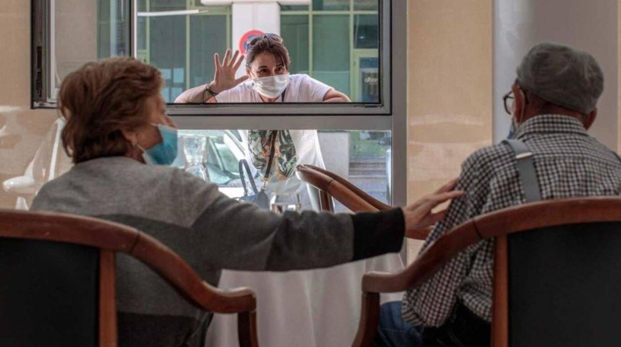 Una mujer visita durante la pandemia a sus familiares desde una ventana en una residencia de ancianos