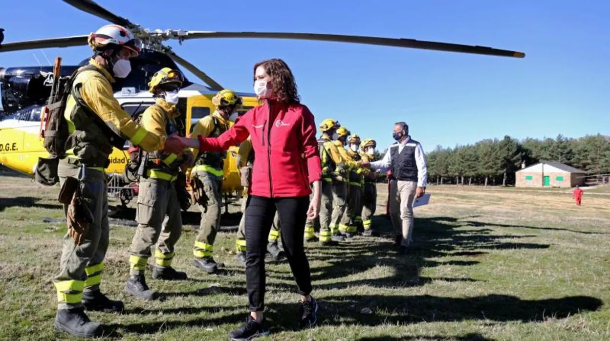 La presidenta de la Comunidad de Madrid, Isabel Díaz Ayuso, y el consejero de Justicia, Interior y Víctimas de la Comunidad de Madrid, Enrique López, saludan a un grupo de bomberos de incendios forestales