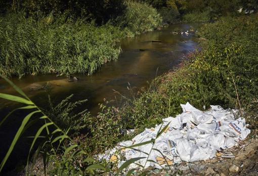 Bolsas con escombros junto al río
