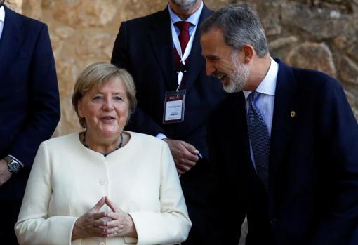 El Rey ríe junto a Merkel, con su habitual gesto de manos