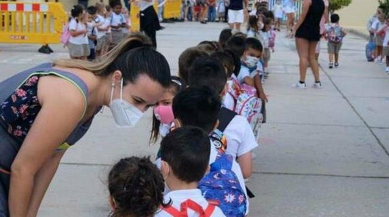 Un grupo de niños con mascarilla en el patio de su colegio