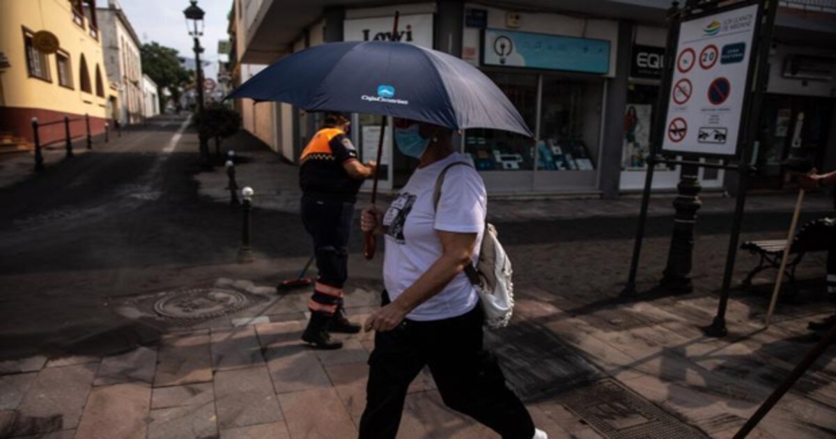 Una mujer pasea en el Valle de Aridane portando un paraguas para protegerse de la ceniza