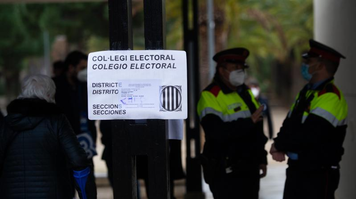 Varios agentes de los Mossos d'Esquadra vigilan un colegio electoral durante la jornada del 14-F en Barcelona