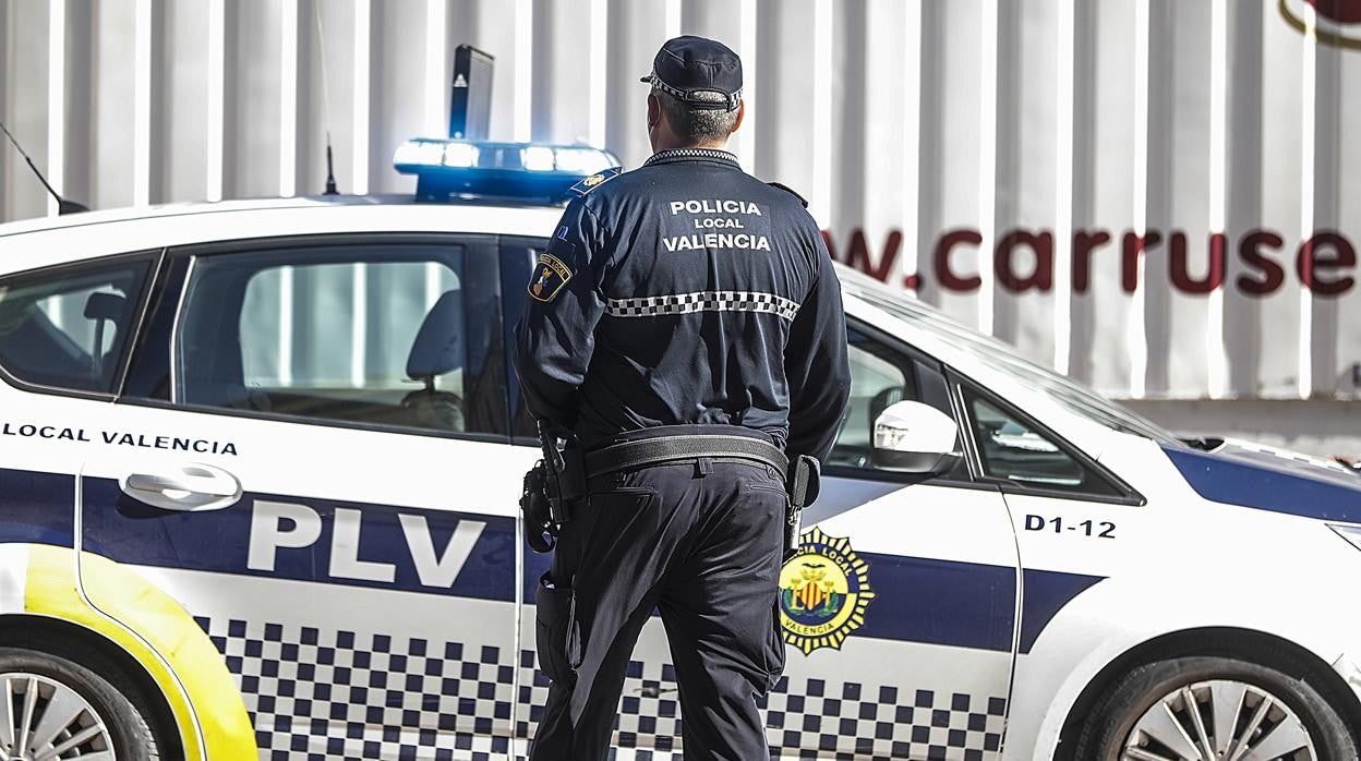 Imagen de archivo de un agente de la Policía Local de Valencia junto a su coche patrulla