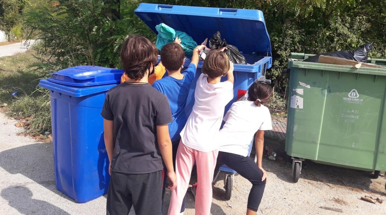Un grupo de niños deposita la basura reciclada en un contenedor