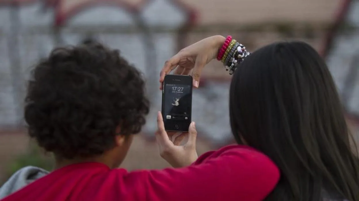 Dos adolescentes miran vídeos en un teléfono móvil
