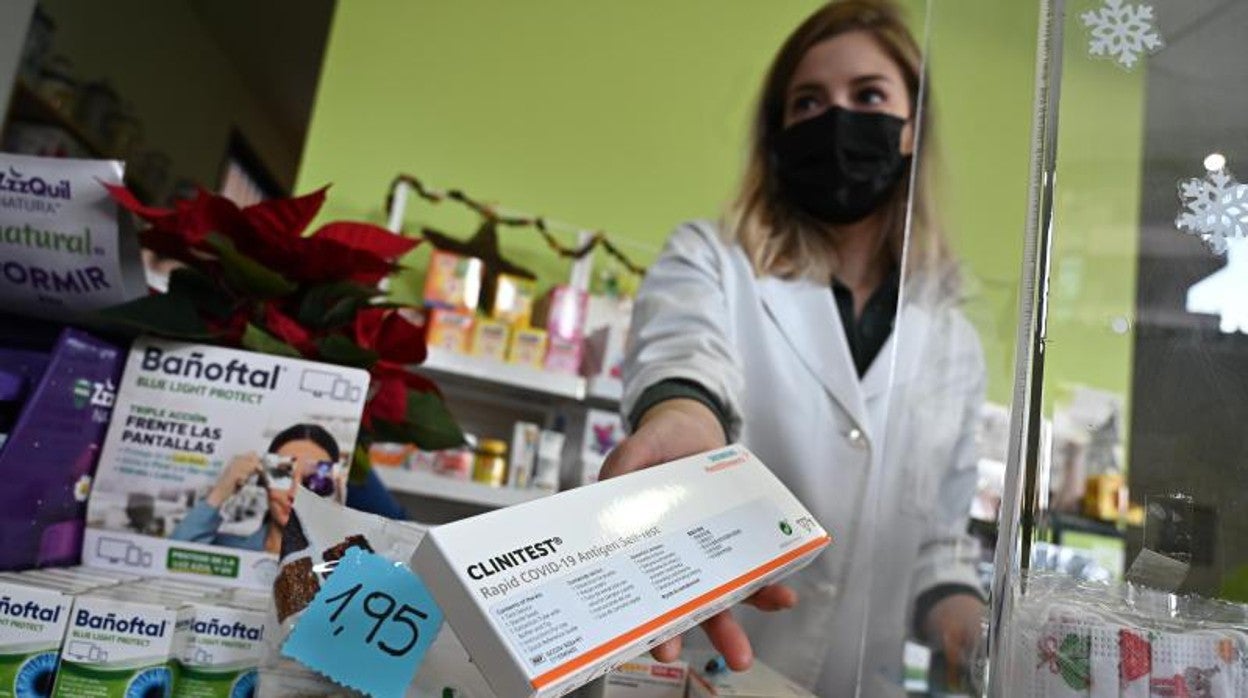 Una farmacéutica entrega un test de antígenos a un cliente